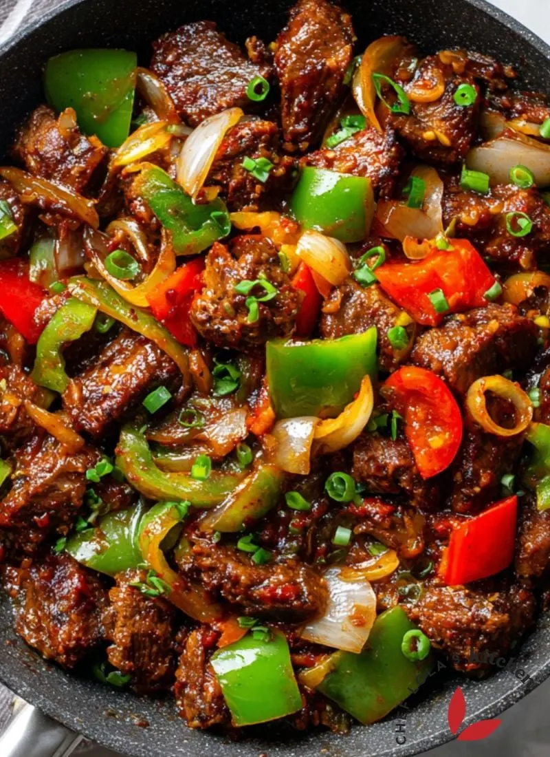 Smoky roasted goat meat (Asun) garnished with onions, chili, and bell peppers.