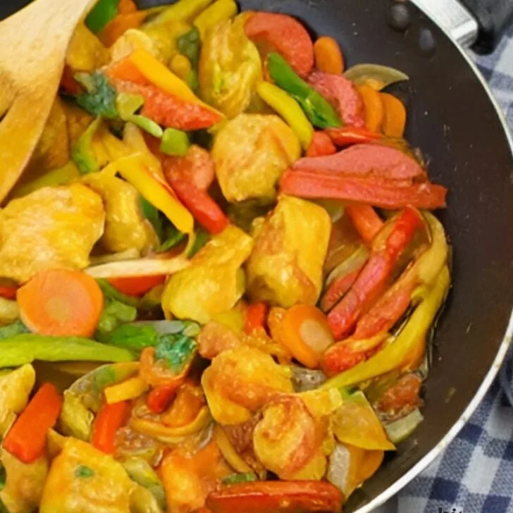 Colorful chicken stir-fry with bell peppers and onions in a skillet.