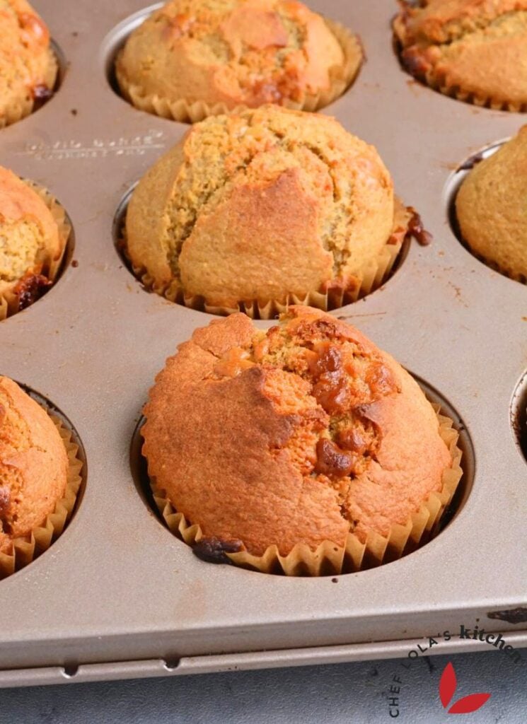 Freshly baked banana oat muffins in a baking tray with a golden top.