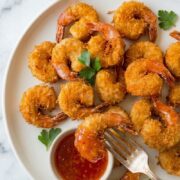 Golden fried coconut shrimp with a crispy coating, served with a side dipping sauce