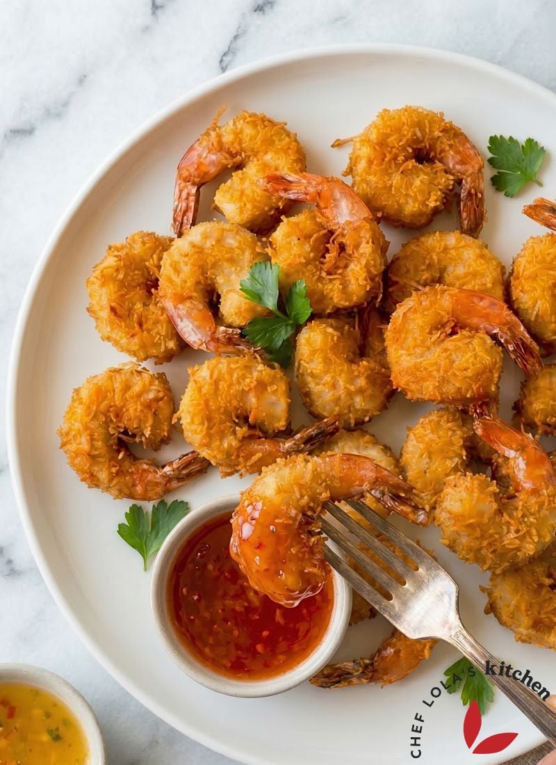 Golden fried coconut shrimp with a crispy coating, served with a side dipping sauce