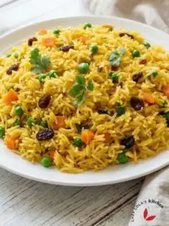 Buttery saffron rice pilaf with separate fluffy grains, garnished with fresh veggies,