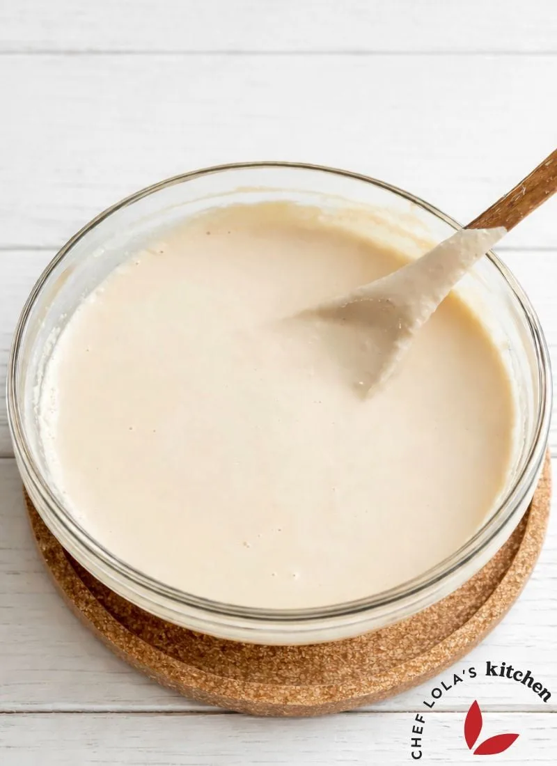 Creamy tahini paste in a small bowl with a wooden spoon.