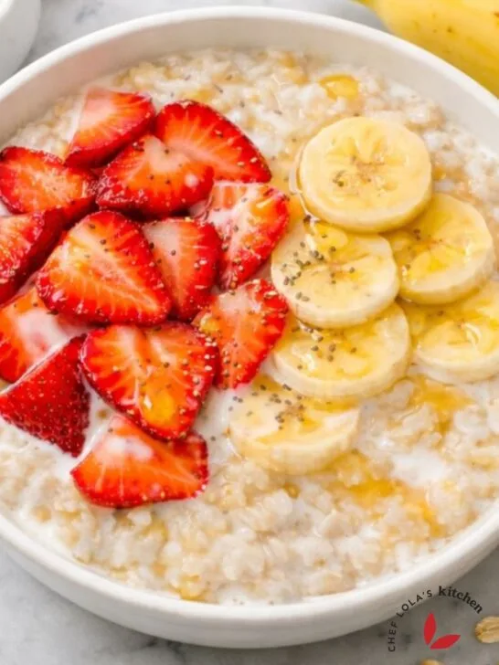 A hearty bowl of oatmeal porridge topped with banana slices, berries and honey