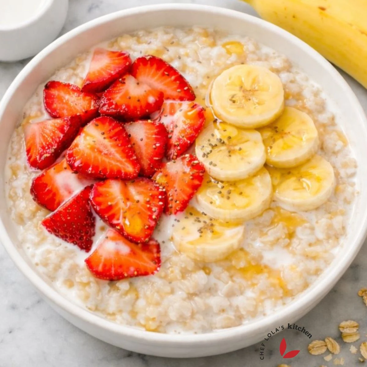 A hearty bowl of oatmeal porridge topped with banana slices, berries and honey