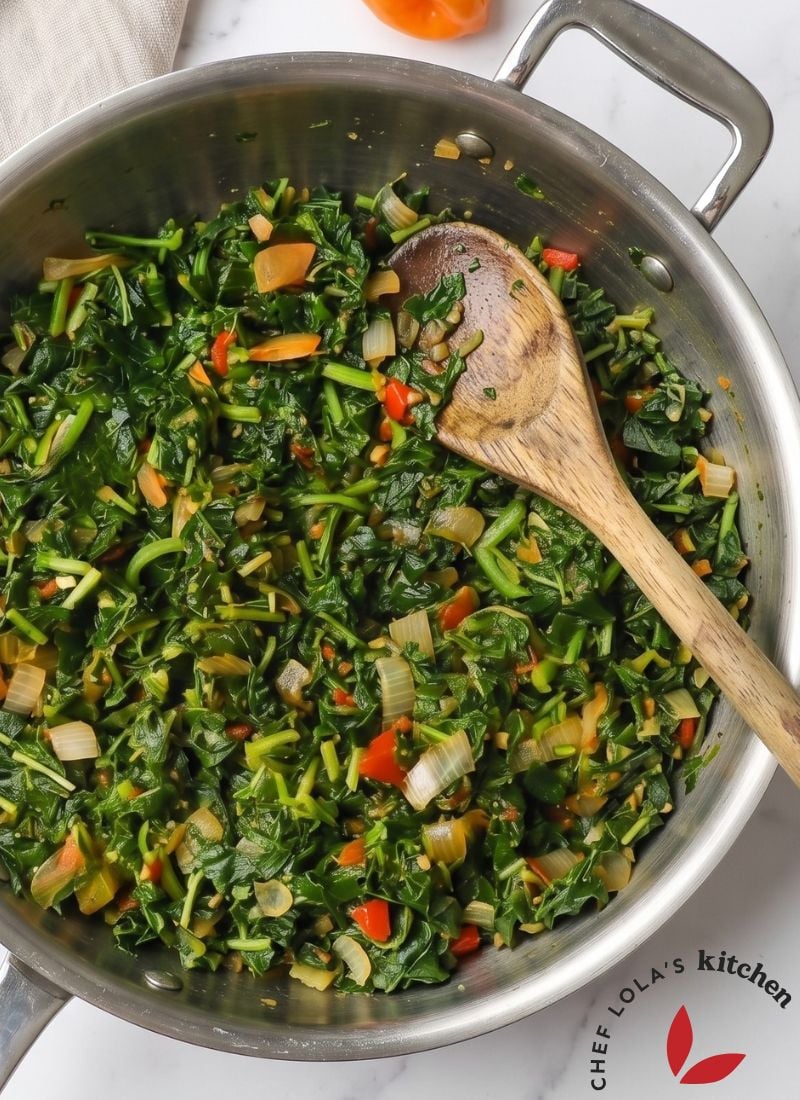 A pot of Jamaican callaloo cooked with onions, tomatoes, peppers, and aromatic seasonings.