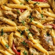Close-up of creamy pasta with Jamaican jerk seasoning and colorful bell peppers.