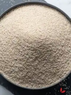 Uncooked fonio grains in a bowl, tiny, nutrient-rich West African grain used for cooking porridge, salad, and side dishes