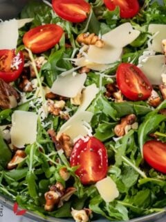 Close-up image of crisp, fresh arugula salad with vinaigrette dressing.