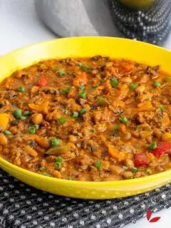 A colorful and enticing plate of beans mixed with savory ground beef, garnished with fresh herbs.