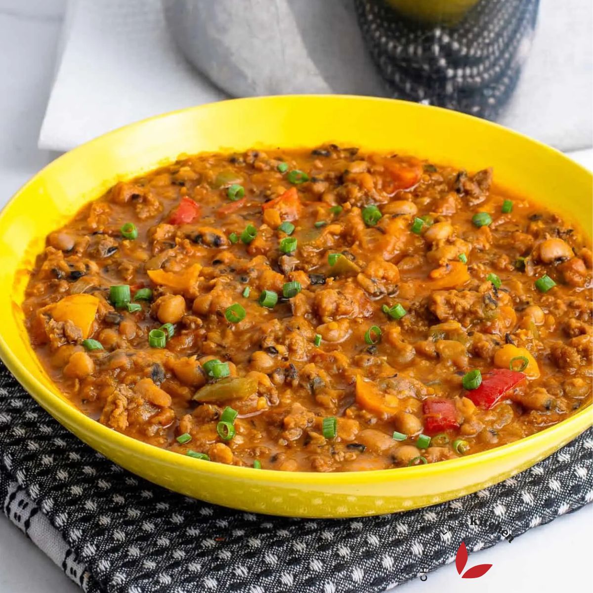 A colorful and enticing plate of beans mixed with savory ground beef, garnished with fresh herbs.