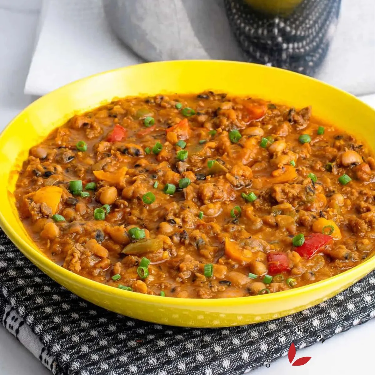 A colorful and enticing plate of beans mixed with savory ground beef, garnished with fresh herbs.