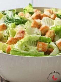 A bowl of Caesar salad made with lettuce and croutons