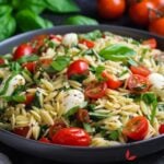 Bowl of Caprese Orzo Salad bursting with bright tomatoes, mozzarella balls, and fresh basil leaves.