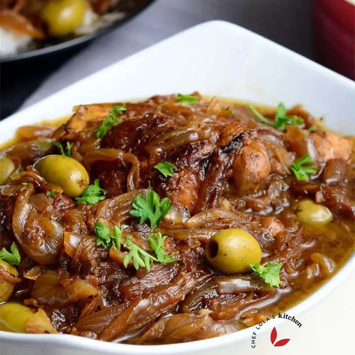Yassa Poulet served in a white bowl and garnished with parsley.