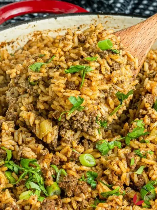 A pot of dirty rice garnished with green onions and parsley.