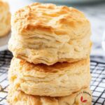 Flaky, fluffy, homemade buttermilk biscuits stacked on a cooling wire rack.