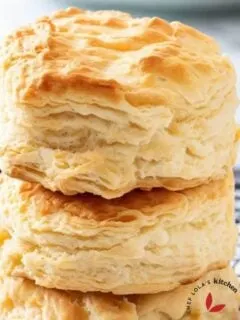 Flaky, fluffy, homemade buttermilk biscuits stacked on a cooling wire rack.