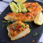 Cod Fish on a black plate garnished with parsley