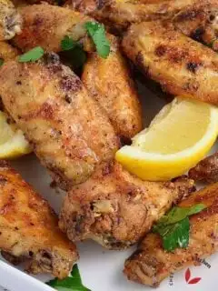 Lemon Pepper Wings in a plate garnished with lemon wedges