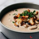 Creamy mushroom soup garnished with mushrooms and fresh herbs.
