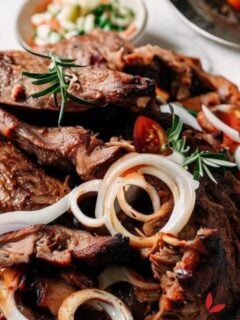 Nyama choma cut and garnished with rosemary, tomatoes and onions