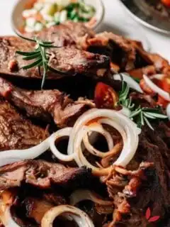 Nyama choma cut and garnished with rosemary, tomatoes and onions