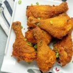 crispy oven fried chicken in a plate and garnished with green onions.
