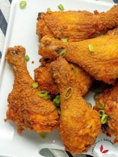 crispy oven fried chicken in a plate and garnished with green onions.