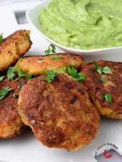 Shrimp cakes served in a large white plate and garnished with parsley.