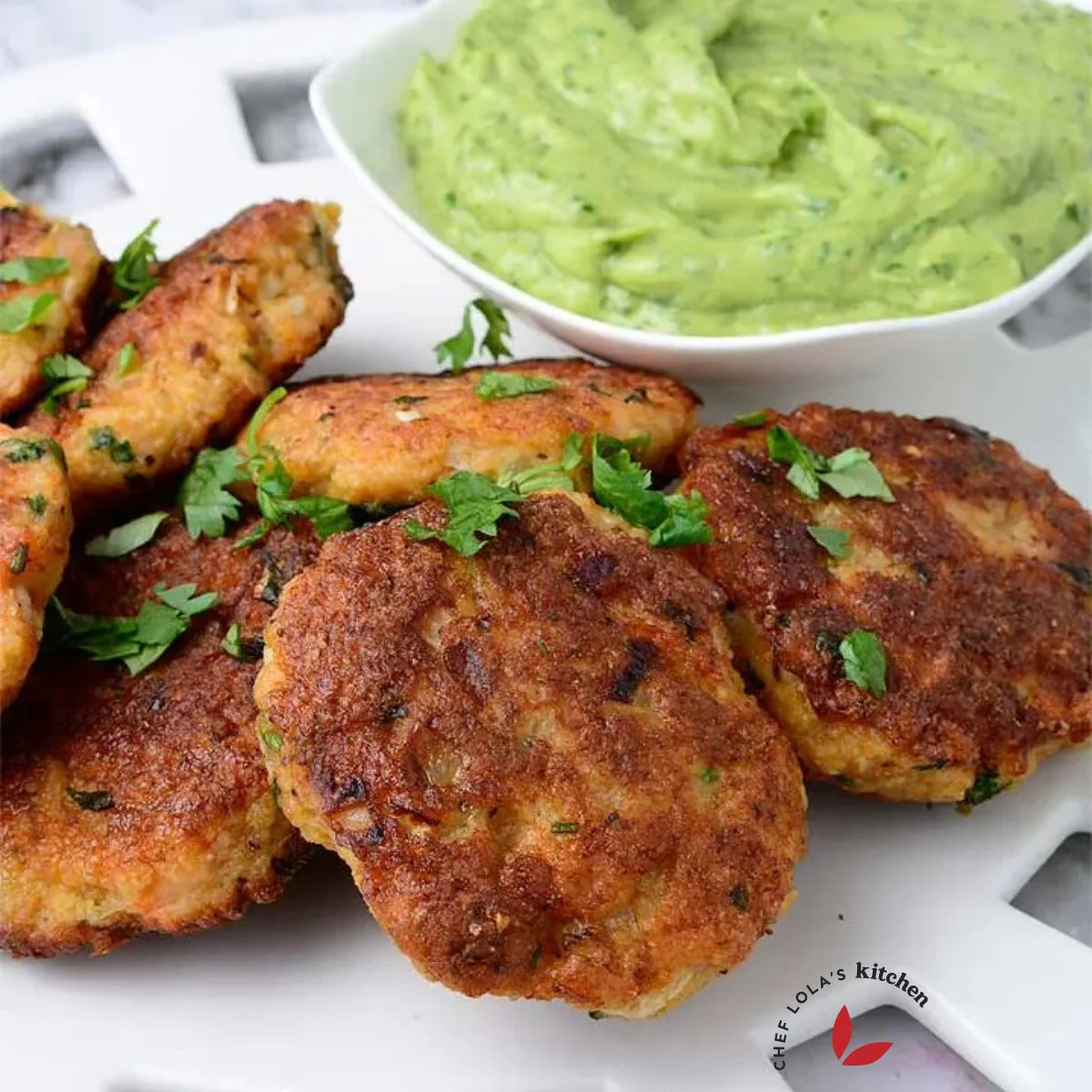 Shrimp cakes served in a large white plate and garnished with parsley.