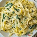Bowl of creamy spinach pasta garnished with parmesan, perfect for a quick weeknight dinner.