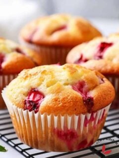 A batch of freshly baked keto-friendly almond flour strawberry muffins cooling on a wire rack.