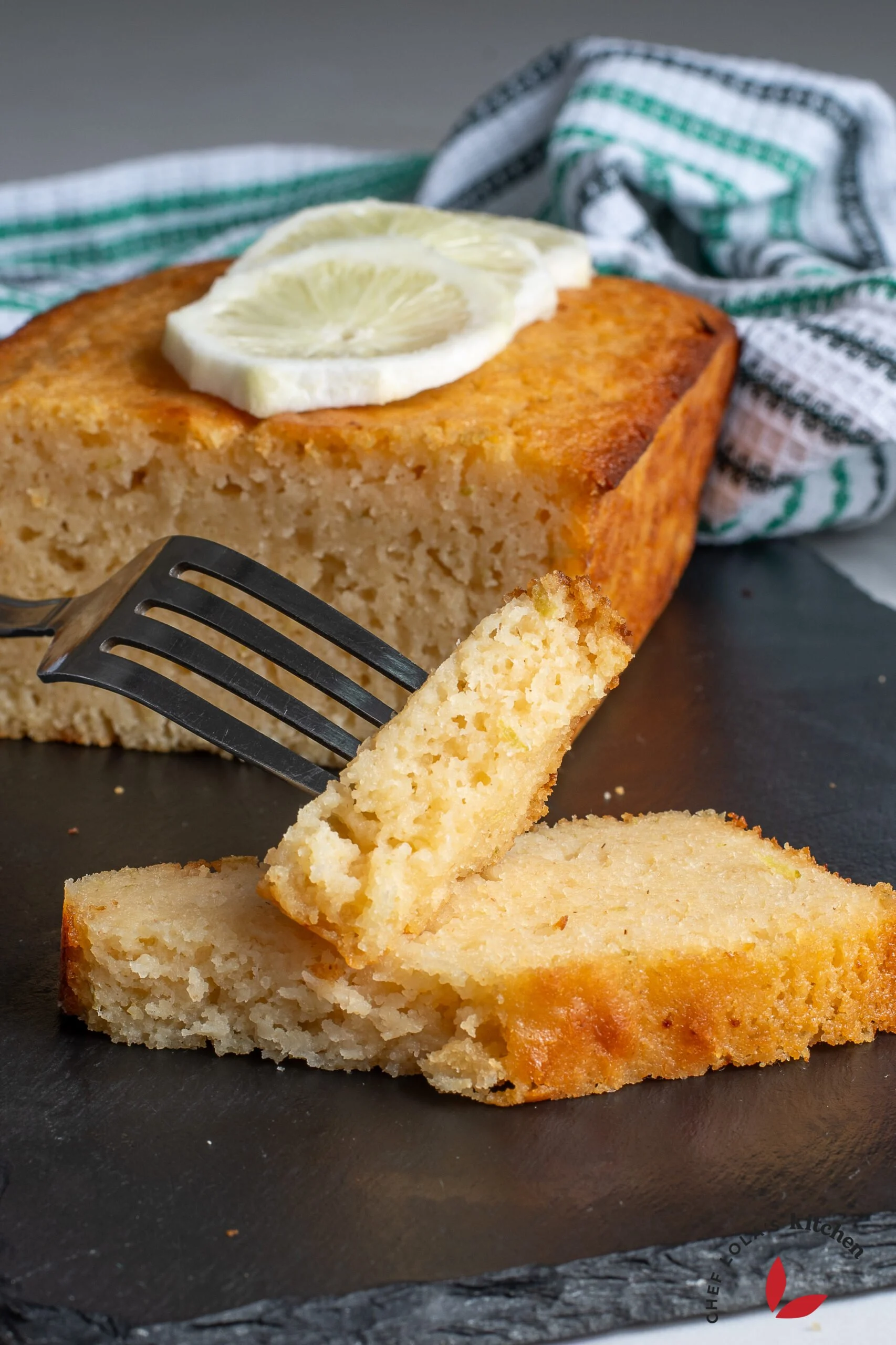 Golden lemon semolina yoghurt cake served on a platter with fresh lemon slices.