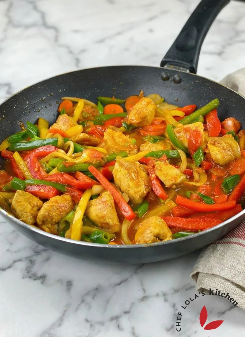 Colorful chicken stir-fry with bell peppers and onions in a skillet.