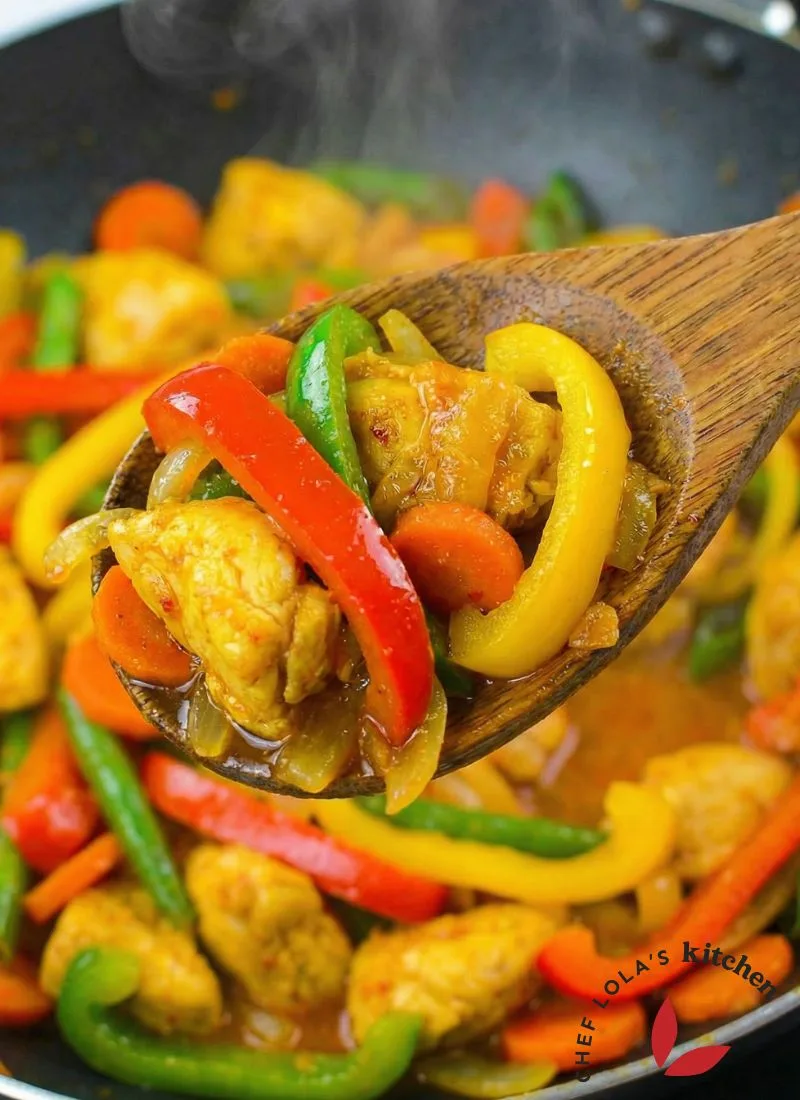 Texture of colorful chicken stir-fry with bell peppers and onions in a skillet.