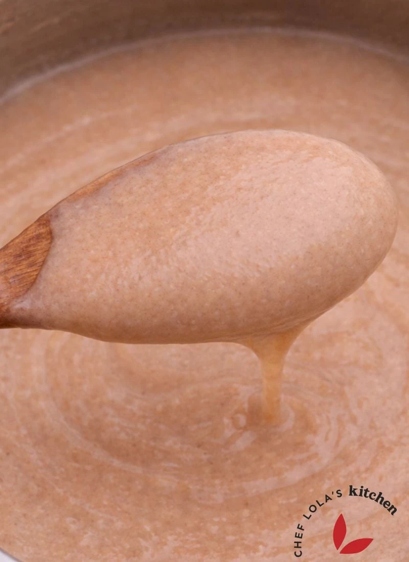 Creamy Nigerian Pap (Ogi) in a bowl with a wooden spoon, highlighting its creamy texture.